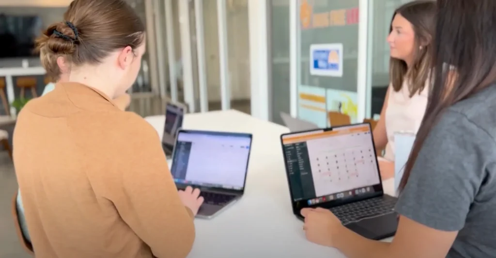 Woman working in a conference setting and looking at laptop screens